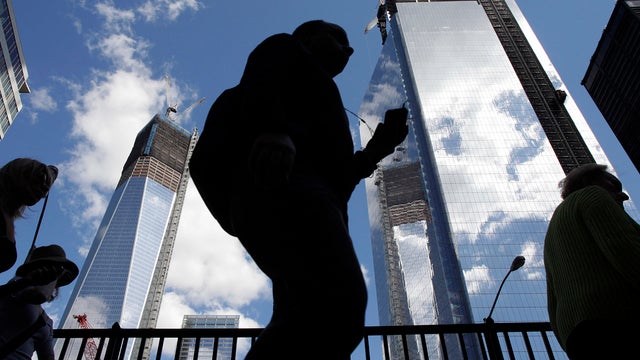 Visitors to the National September 11 Memorial walk below the rising towers 1 World Trade Center, left, and 4 World Trade Center, Monday, Sept. 10, 2012 in New York. Tuesday will mark the eleventh anniversary of the attacks of Sept. 11, 2001. 