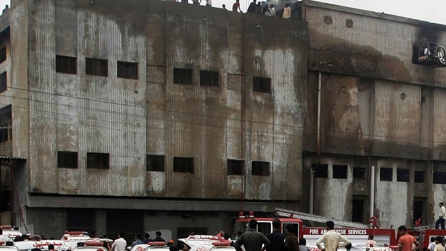 People gather as rescue work continues at burnt garment factory in Karachi, Pakistan Wednesday 