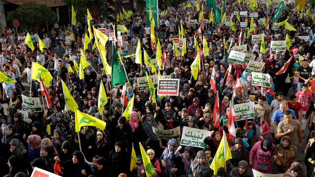 Hezbollah supporters wave flags and hold up Arabic banners reading "At your service God's prophet, America equals terrorism, and America does not equal freedom" during a rally in Beirut Sept. 17, 2012, denouncing an anti-Islam film that has provoked a wee 