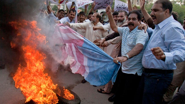 Pakistani traders burn a representation of a U.S. flag 