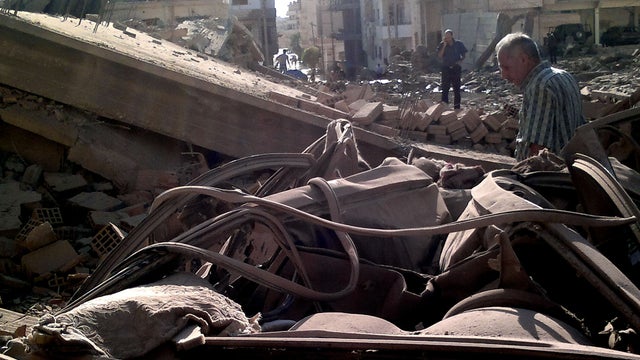 Syrian men inspect the scene of a car bomb attack in Qamishli, 497 miles northeast Damascus, Syria, Sunday, Sept. 30, 2012. 