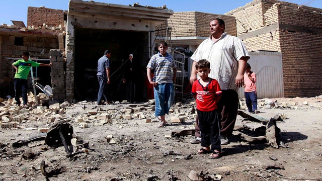 Iraqis stand in rubble at the scene of a car bomb attack in the town of Taji, about 12 miles north of Baghdad, Iraq, Sunday, Sept. 30, 2012. 