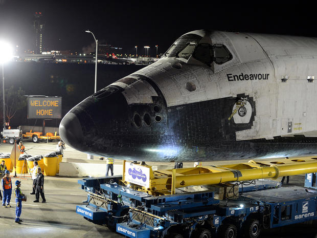 Space shuttle Endeavour passes a "Welcome Home" sign as it begins its journey to its permanent home in Los Angeles in the early morning hours Oct. 12, 2012, at Los Angeles International Airport. 