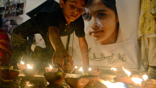A Pakistani youth places an oil lamp next to a photograph of child activist Malala Yousafzai, who was shot in the head in a Taliban assassination attempt, during a tribute in Karachi, Pakistan, Oct. 12, 2012. 
