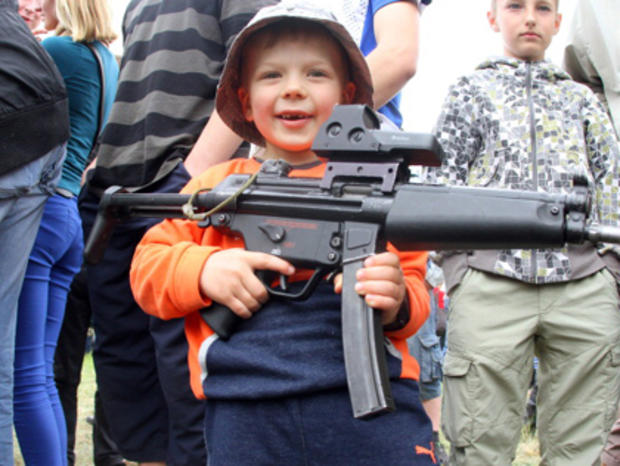 A small boy holds a large gun  during 