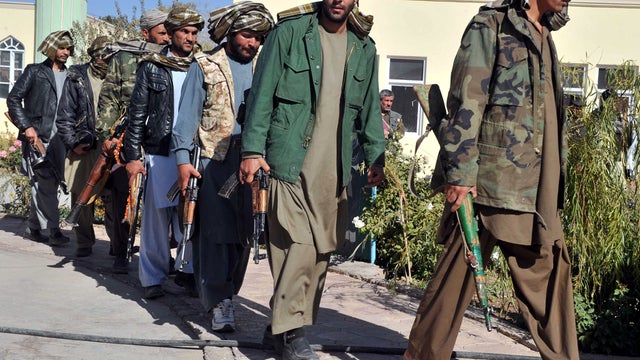 Former Taliban fighters walk with their weapons after they joined Afghan government forces during a ceremony in Herat, Afghanistan, Oct. 22, 2012. 