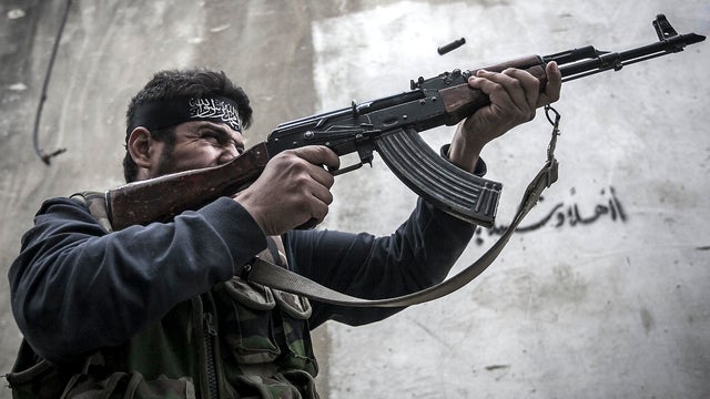 A Free Syrian Army fighter shoots his gun toward government troops as rebel fighters belonging to the Liwa Al Tawhid group carry out a military operation at the Moaskar front line, one of the battlefields in the Karmal Jabl neighborhood in Aleppo, Syria,  