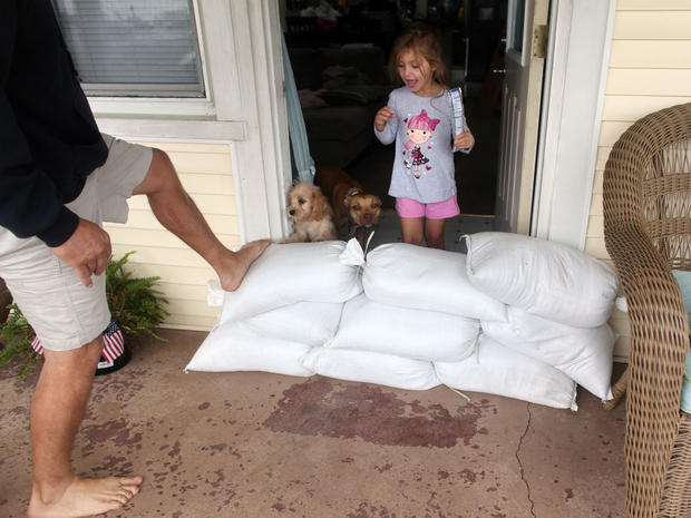 Hannah Smith, 4, looks over a pile of sandbags as her dad, Charles, checks their stability in front of their Norfolk, Va.,  home  