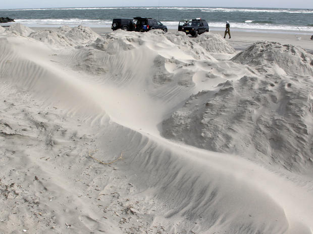 As men surf fish near the ocean, sand blows  on mounds for beach protection in North Wildwood, N.J. 