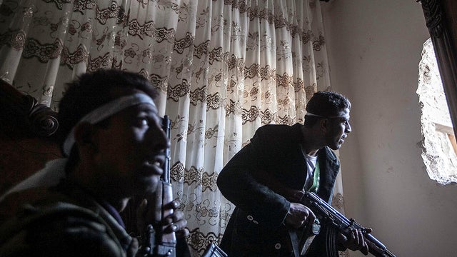 In this Nov. 1, 2012 photo, rebel fighters watch over enemy positions as they wait for Syrian army troops to enter a street during clashes in the Karmal Jabl battlefield in Aleppo, Syria.  