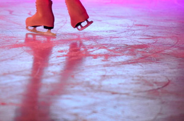 A child figure skates on an outdoor ice- 
