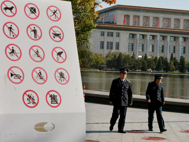 Chinese security officers patrol a park next to the Great Hall of the People 