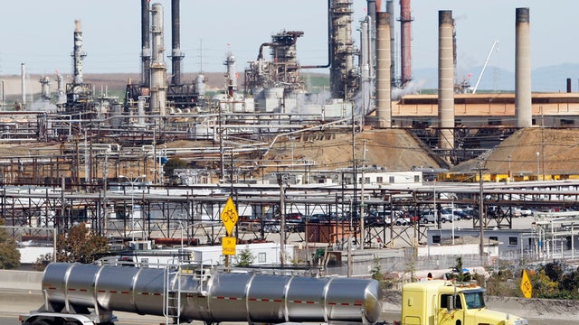 March 9, 2010 file photo shows a tanker truck passing the Chevron oil refinery in Richmond, Calif. On Weds., Nov. 14, 2012, California&acirc;??s largest greenhouse gas emitters will for the first time begin buying permits in a landmark &acirc;??cap-and-trade&acirc;?? syste 