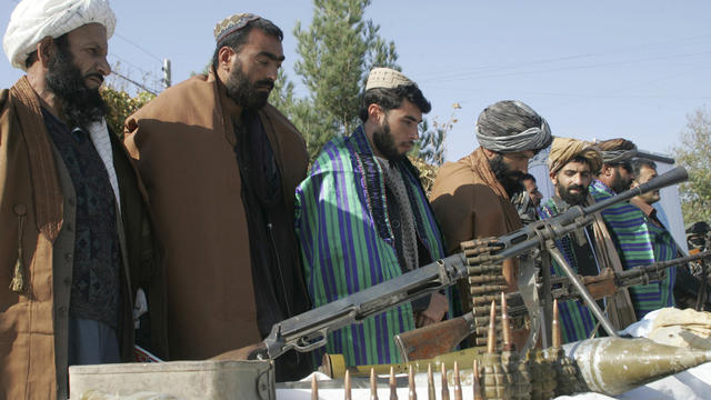 Taliban fighters line up to hand over their weapons to join the peace process in Herat 