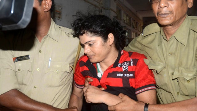 Police escort former Indian athlete Pinki Pramanik, center, to Barasat District Court in Barasat, India, June 15, 2012. 