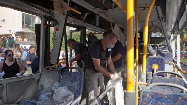 Israeli police officers examine a bus destroyed by a bomb in Tel Aviv 