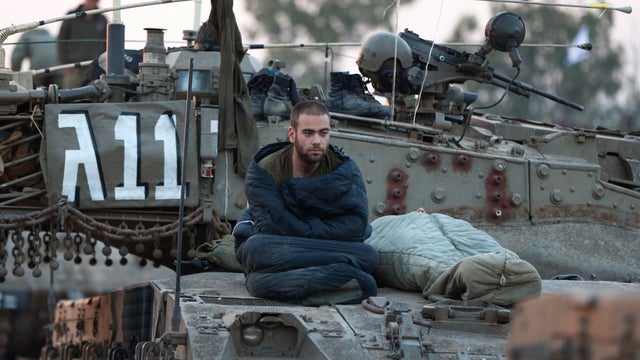An Israeli soldier sits after he woke up atop a tank at a staging area near the Israel Gaza Strip Border, southern Israel, Thursday, Nov. 22, 2012.   