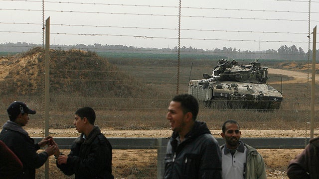 Israeli tank keeps watch over the Gaza border as Palestinians gather near the fence on the other side 