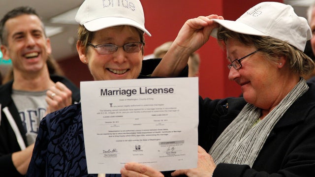 Claudia Gorbman, left, and partner Pam Keeley wear caps both reading "bride" as they display their newly-issued marriage license, Thursday, Dec. 6, 2012, in Seattle. King County Executive Dow Constantine began issuing the licenses immediately upon certifi 