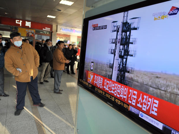 Travellers watch a TV screen broadcasting news about North Korea's rocket launch, at a railway station in Seoul on December 12, 2012. North Korea on December 12 launched a long-range rocket which Japanese authorities said passed over its southern island c 