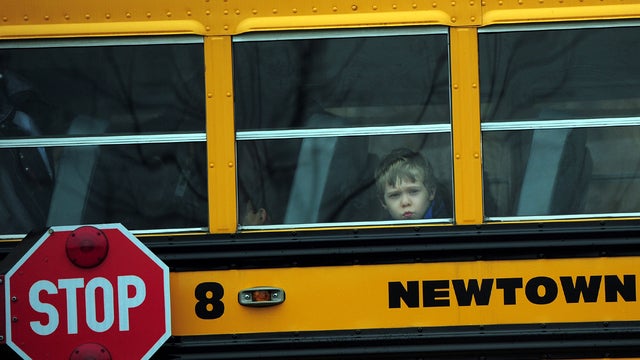 A child looks out of a bus window as it passes by St. Rose of Lima Catholic Church, where the funeral of James Mattioli, 6, was taking place Dec. 18, 2012, in Newtown, Conn. 
