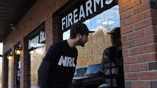 Shawn Cavana, a member of the National Rifle Association who says he personally owns an AR-15 semi-automatic rifle, looks into the closed Riverview Gun Sales shop while gun shopping with friends Dec. 21, 2012, in East Windsor, Conn. 