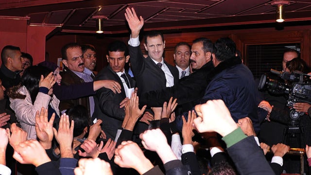 In this photo released by the Syrian official news agency SANA, Syrian President Bashar Assad, top center, waves to his supporters after speaking at the Opera House in central Damascus, Syria, Sunday, Jan. 6, 2013. 