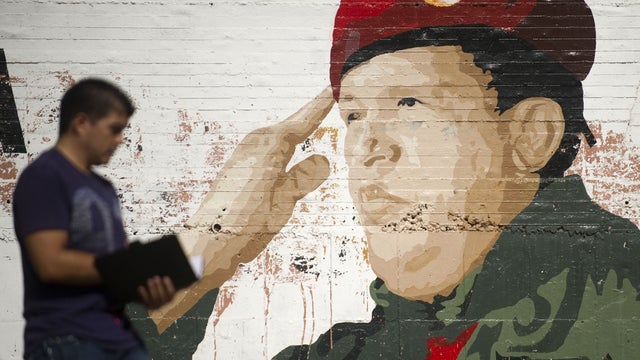A man walks by a mural of Venezuelan President Hugo Chavez  