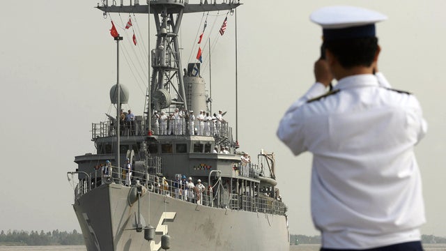 A Vietnamese navy officer takes a picture of the USS Guardian approaching Hai Phong, Vietnam, Nov. 14, 2007. 