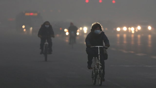 Beijing residents wearing masks ride amid fog during severe pollution on January 29, 2013. China 