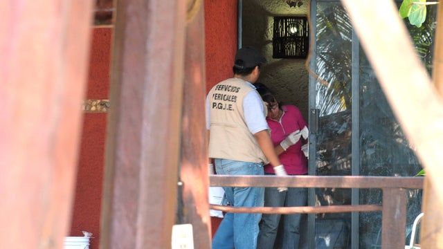 Police investigators work to obtain fingerprints on a door at the home where masked, armed men broke in, in Acapulco, Mexico, Tuesday Feb. 5, 2013. According to the mayor of Acapulco, five masked men burst into this house that Spanish tourists had rented  