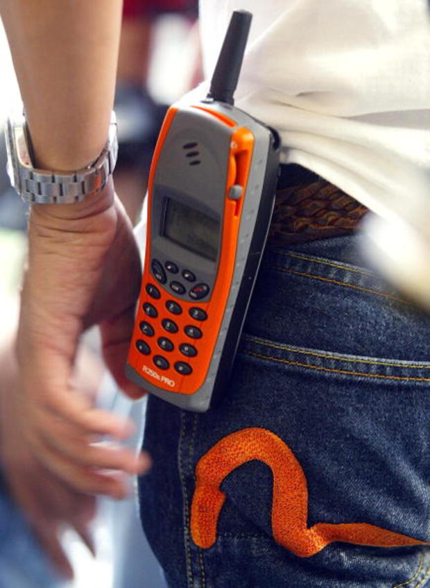 A mobile phone hangs from colour-coordinated jeans 