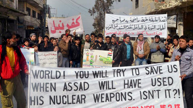 This citizen journalism image provided by Edlib News Network, ENN, which has been authenticated based on its contents and other AP reporting, shows anti-Syrian regime protesters carry banners during a demonstration, at Kafr Nabil town, in Idlib province,  