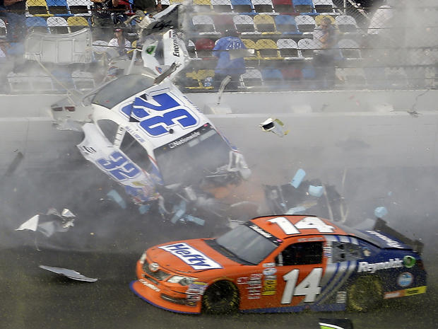 Kyle Larson (32) slides along the wall after hitting the catch fence as Eric McClure (14) goes low after the cars were involved in a multi-car crash on the final lap of the NASCAR Nationwide Series auto race at Daytona International Speedway Feb. 23, 2013 
