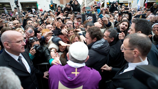 In this photo provided by the Vatican paper L'Osservatore Romano, Pope Francis greets faithful from a side gate of the Vatican, Sunday, March 17, 2013. 