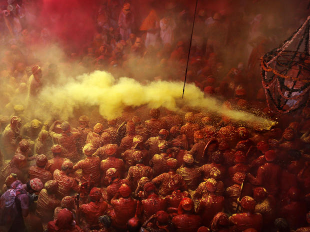 Hindu men from the village of Nandgaon, India, are covered in colored powder as they sit on the floor during prayers at the Ladali, or Radha, temple before the procession for the Lathmar Holi festival in the legendary hometown of Radha, consort of Hindu g 