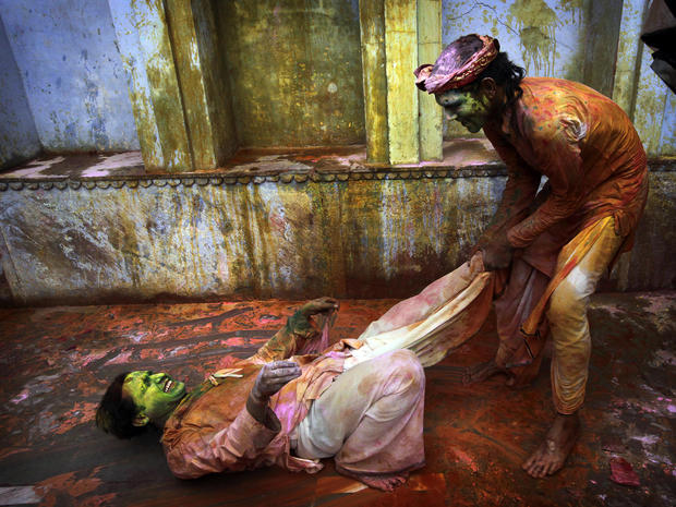 Indian Hindu devotees smeared with colors play at the Nandagram temple, famous for Lord Krishna and his brother Balram, during Lathmar Holi festival in Nandgaon, India, 75 miles from New Delhi, March 22, 2013. During Lathmar Holi the women of Nandgaon, th 