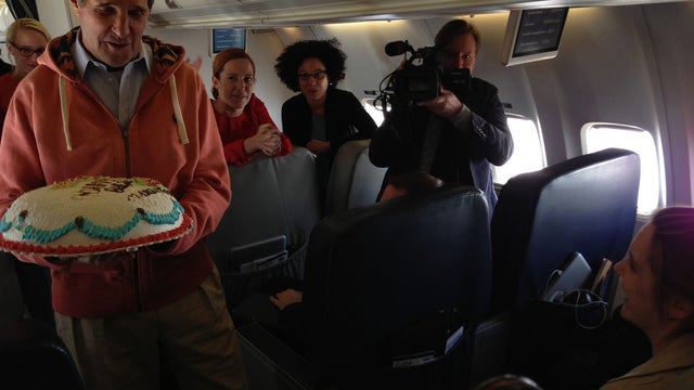U.S. Secretary of State John Kerry presents a birthday cake to CBS News State Department correspondent Margaret Brennan, as they marked her birthday while flying from Kabul, Afghanistan, to Paris, France, March 26, 2013.  