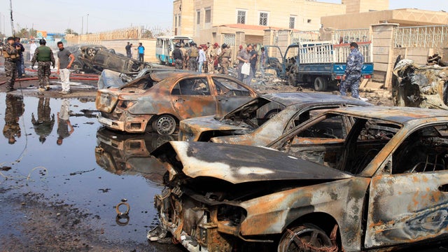 Civilians and security forces personnel gather at the scene of a car bomb attack in Baghdad, Iraq, on March 29, 2013. 