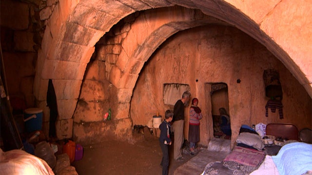 Syrians stand inside their cave home in Jabel Zawiya's "Dead Cities" 