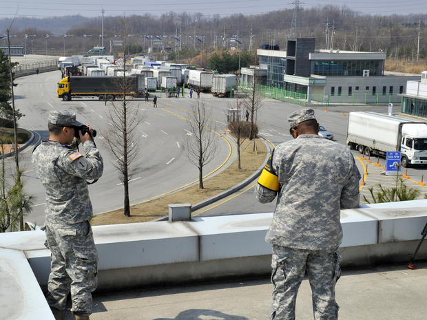 U.S. soldiers take pictures as South Korean trucks turn back at a border crossing in Paju 