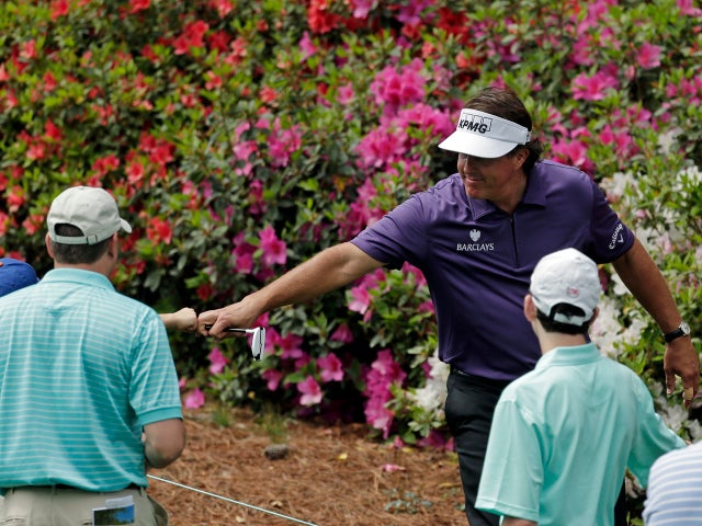 Phil Mickelson touches a young spectator's fist as he walks down the sixth fairway during the second round of the Masters golf tournament April 12, 2013, in Augusta, Ga. 