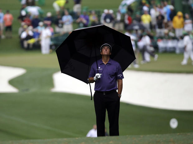 Phil Mickelson looks up from his umbrella during a rain storm on the first hole during the second round of the Masters golf tournament April 12, 2013, in Augusta, Ga. 