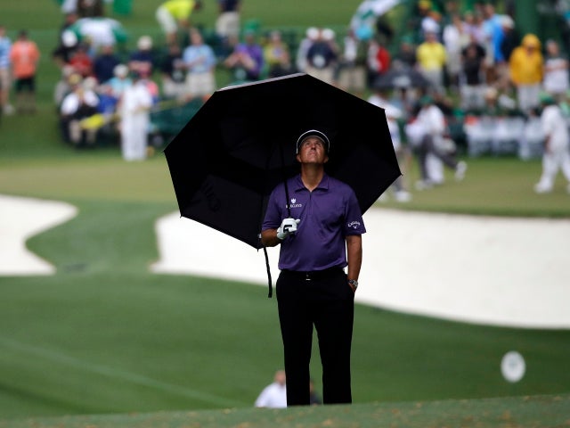 Phil Mickelson looks up from his umbrella during a rain storm on the first hole during the second round of the Masters golf tournament April 12, 2013, in Augusta, Ga. 