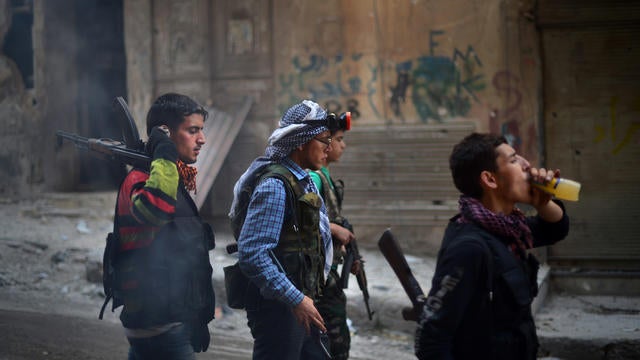 Syrian and Kurdish rebel fighters walk in Aleppo 