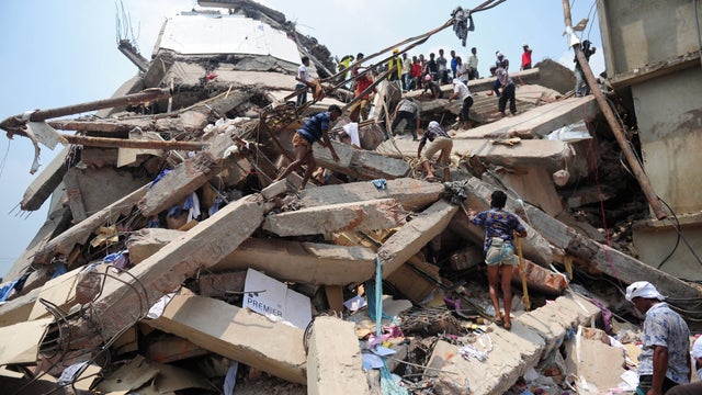 Bangladeshi volunteers and rescue workers climb on rubble after an eight-story building collapsed 