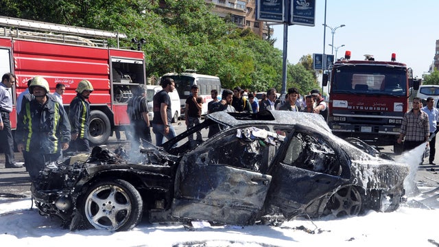 Photo released by Syrian official news agency SANA shows Syrian firefighters extinguishing burning cars after car bomb exploded in capital's western neighborhood of Mazzeh, in Damascus, April. 29, 2013. State-run Syrian TV says the country's prime ministe 