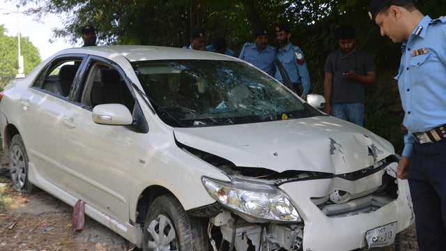 Pakistani police officials examine bullet-riddled car of slain government prosecutor Chaudhry Zulfiqar after an attack by gunmen in Islamabad on May 3, 2013 