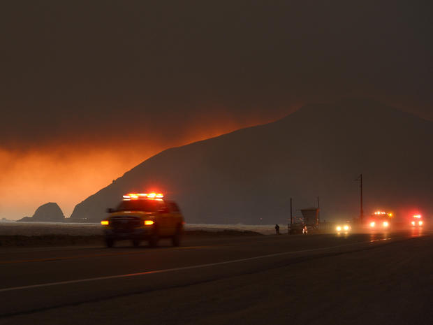 Fire department personnel drive along the Pacific Coast Highway near Point Mugu as a thick layer of smoke sits overhead during a wildfire that burned several thousand acres May 2, 2013, in Ventura County, Calif. 