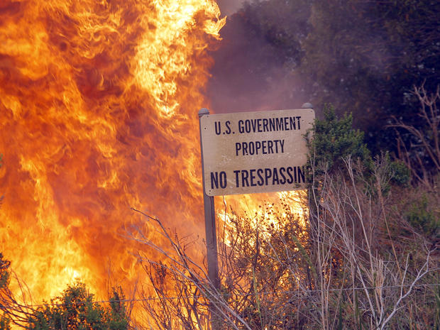 A brush fire burns a sign at a shooting range on the beach at Naval Base Ventura County in Southern California May 3, 2013. 